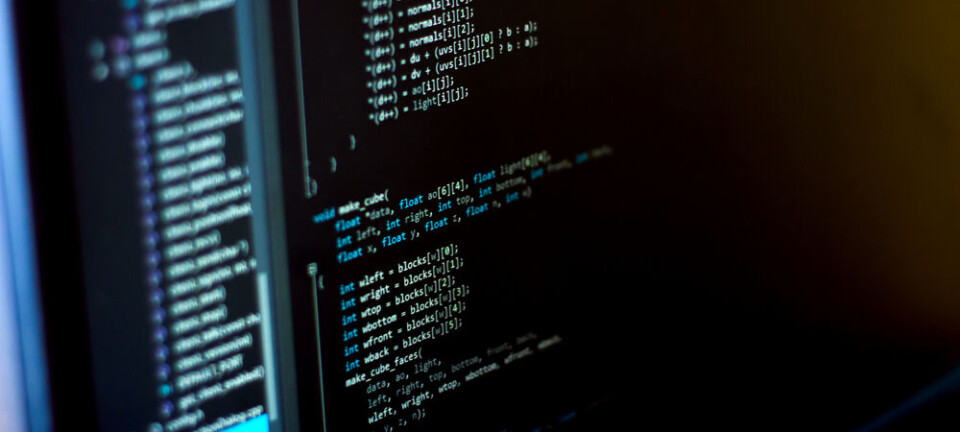 Monitor displaying C programming code and file tree in a dark code editor.