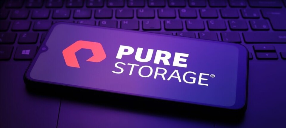 Pure Storage logo on a smartphone lying across a laptop keyboard in purple light