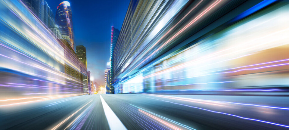 Blurred light trails on a city street between tall buildings at night